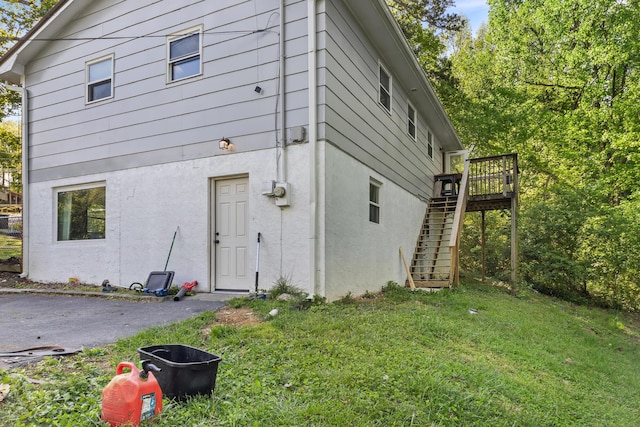 rear view of house featuring stairway, a yard, and a deck