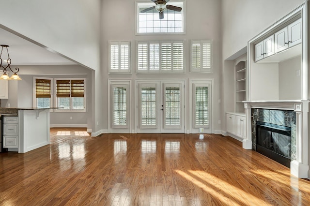 unfurnished living room with french doors, a fireplace, a towering ceiling, and wood finished floors