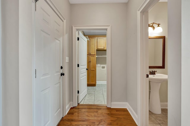 corridor with light wood-style flooring and baseboards