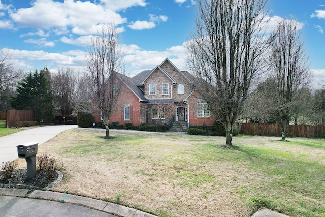 view of front of home with a front yard, fence, and brick siding