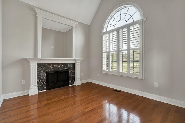 unfurnished living room featuring baseboards, lofted ceiling, a fireplace, and hardwood / wood-style flooring