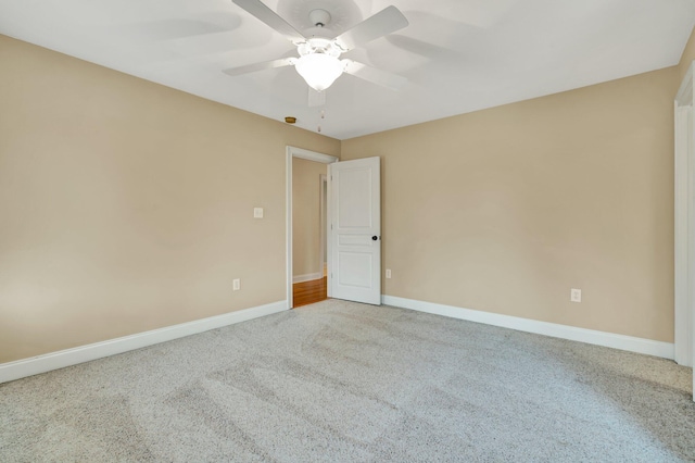 carpeted spare room featuring ceiling fan and baseboards