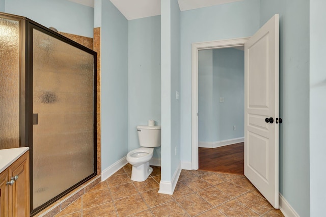 bathroom featuring tile patterned flooring, toilet, baseboards, and a stall shower