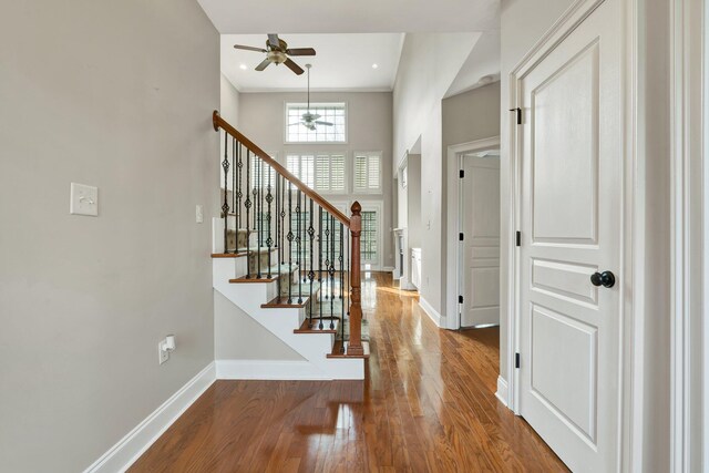 entrance foyer with stairway, baseboards, wood finished floors, and a towering ceiling