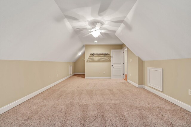 additional living space featuring light colored carpet, a ceiling fan, baseboards, and vaulted ceiling