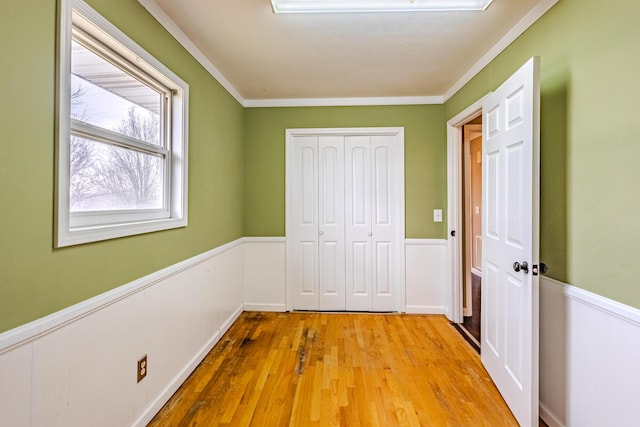 unfurnished bedroom featuring crown molding, light hardwood / wood-style flooring, and a closet