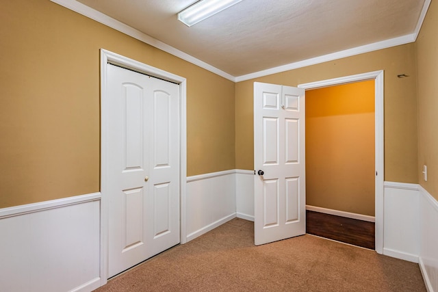 unfurnished bedroom featuring light carpet, ornamental molding, and a closet