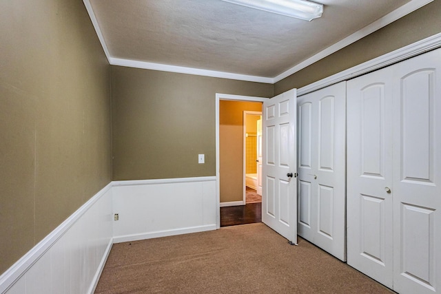 unfurnished bedroom featuring crown molding, a closet, a textured ceiling, and carpet