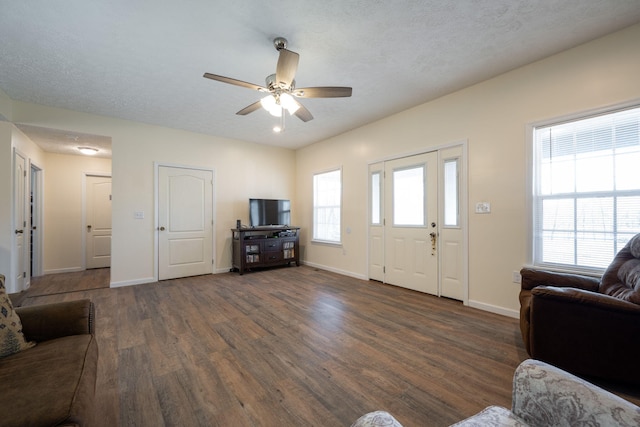 living room with a textured ceiling, ceiling fan, and dark hardwood / wood-style floors