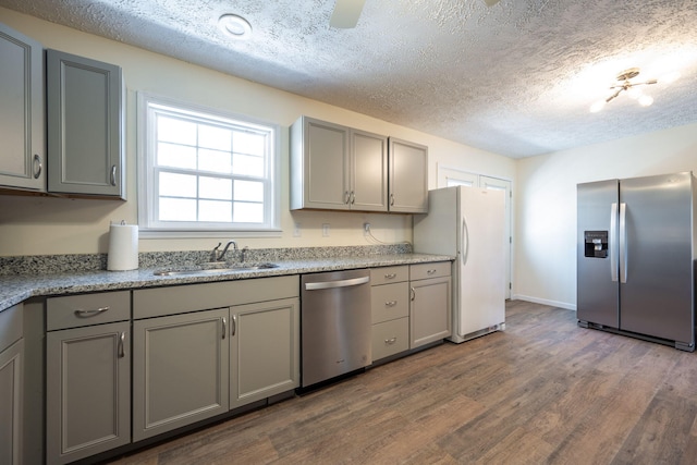 kitchen featuring appliances with stainless steel finishes, gray cabinetry, a textured ceiling, sink, and hardwood / wood-style floors