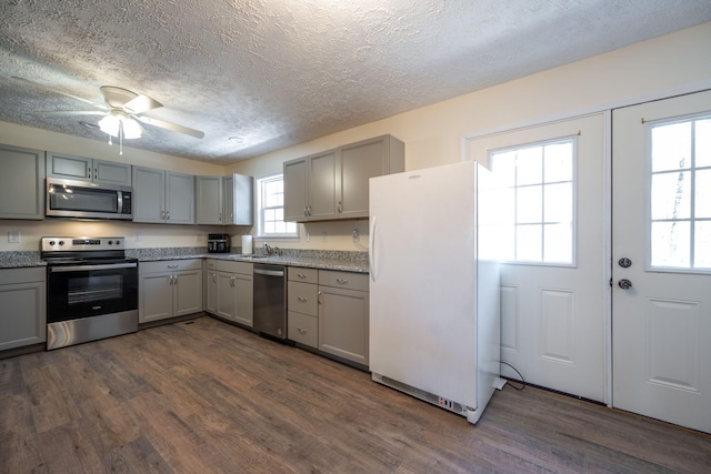 kitchen featuring a textured ceiling, dark hardwood / wood-style floors, gray cabinets, and stainless steel appliances