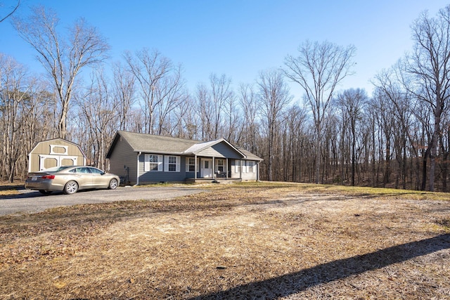 view of front of house featuring covered porch, a garage, and a storage shed