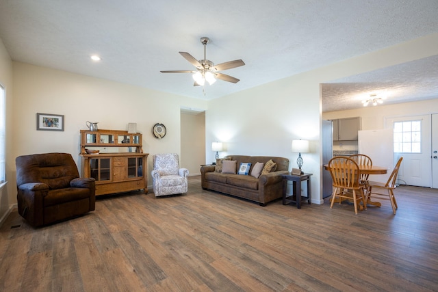 living room with dark hardwood / wood-style floors, ceiling fan, and a textured ceiling