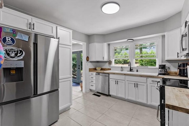 kitchen featuring white cabinets, stainless steel appliances, and wood counters