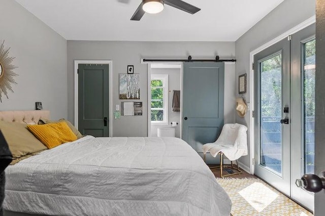 bedroom featuring access to exterior, a barn door, hardwood / wood-style flooring, and ceiling fan