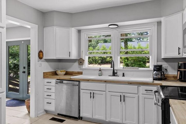 kitchen featuring white cabinets, sink, light tile patterned floors, appliances with stainless steel finishes, and butcher block counters