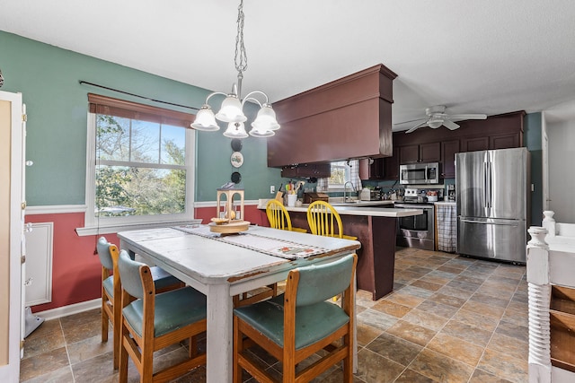 dining area with ceiling fan with notable chandelier, a healthy amount of sunlight, and sink