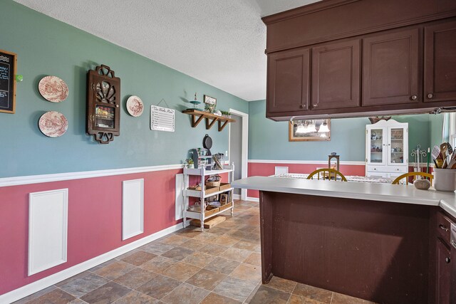 kitchen featuring dark brown cabinets and a textured ceiling