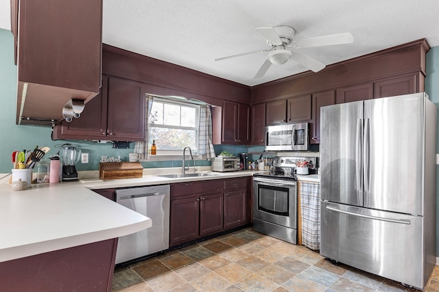 kitchen with a textured ceiling, ceiling fan, sink, and appliances with stainless steel finishes