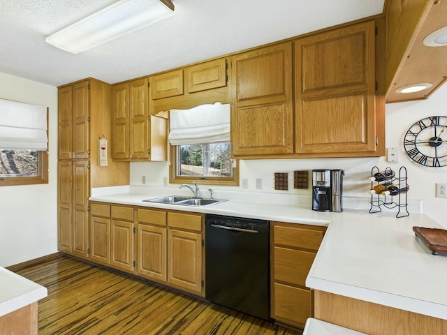 kitchen with brown cabinets, black dishwasher, light countertops, and a sink