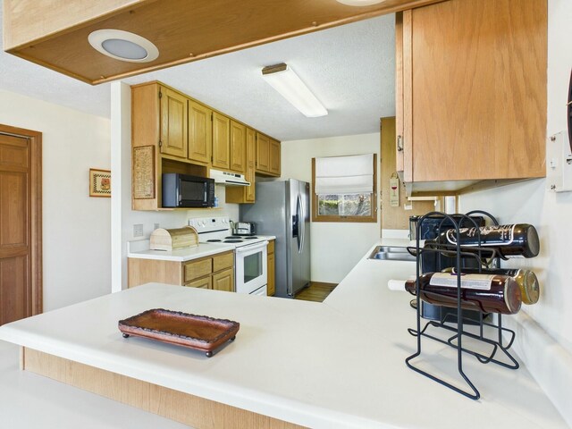 kitchen with under cabinet range hood, white range with electric stovetop, black microwave, and light countertops