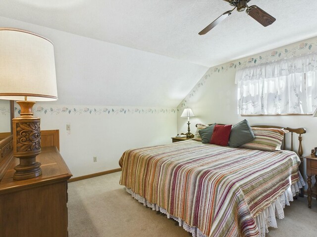 bedroom featuring lofted ceiling, ceiling fan, a textured ceiling, light carpet, and baseboards