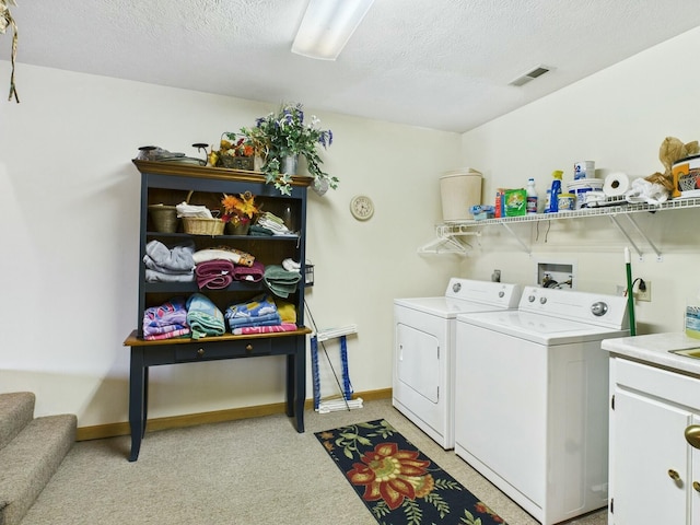 washroom featuring cabinet space, visible vents, baseboards, a textured ceiling, and washing machine and dryer