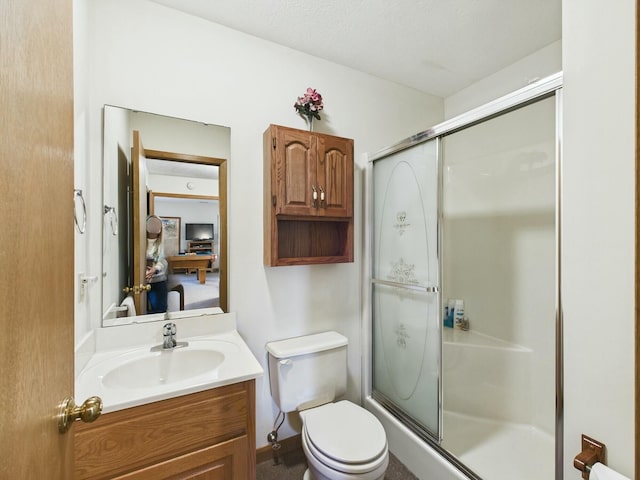 bathroom featuring toilet, a shower with door, and vanity