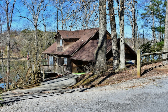 view of side of home featuring roof with shingles and driveway