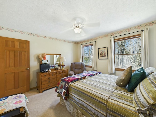 bedroom with light carpet, ceiling fan, and a textured ceiling