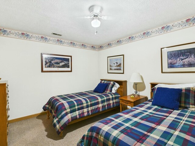 carpeted bedroom with visible vents, a textured ceiling, and baseboards