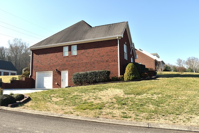 view of side of home featuring a garage, brick siding, and a lawn