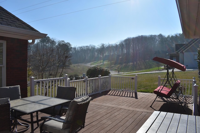 wooden terrace featuring outdoor dining space and a yard