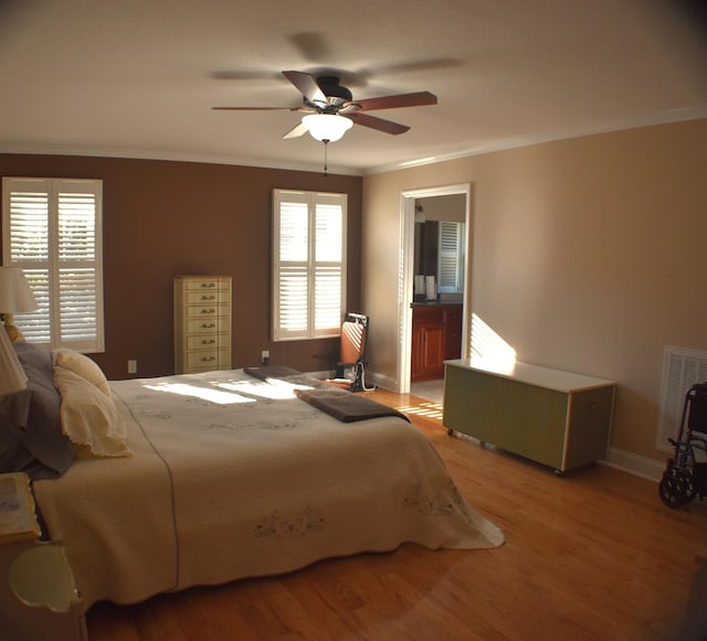 bedroom with a ceiling fan, visible vents, baseboards, ornamental molding, and light wood-style floors