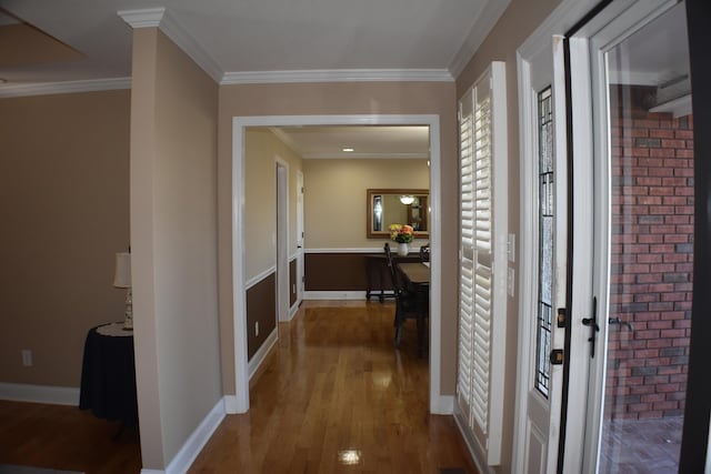 hall with baseboards, wood finished floors, and ornamental molding