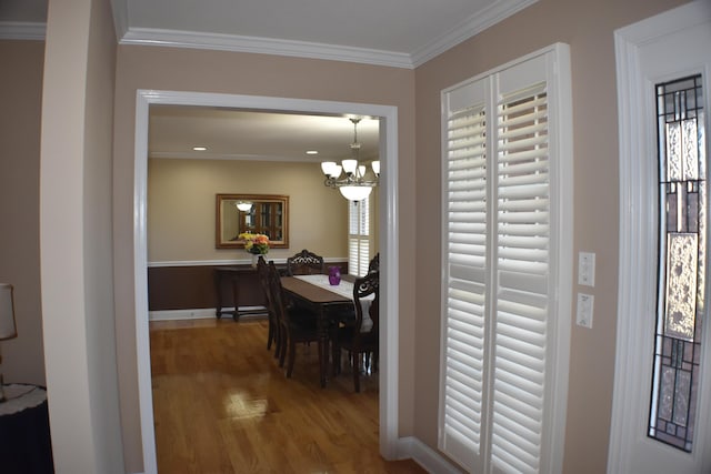 hall featuring an inviting chandelier, crown molding, and wood finished floors