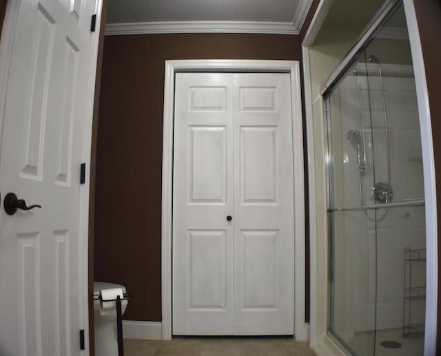 bathroom featuring tile patterned flooring, a shower stall, baseboards, and ornamental molding