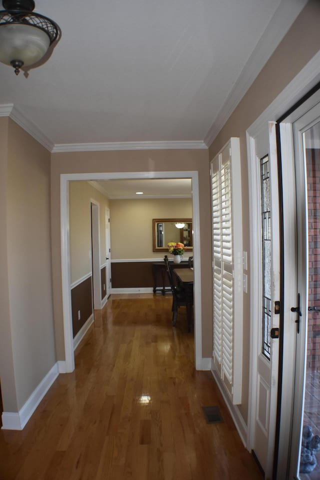 foyer featuring visible vents, ornamental molding, baseboards, and wood finished floors