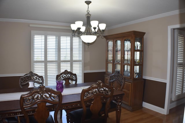 dining space featuring an inviting chandelier, wood finished floors, crown molding, and baseboards