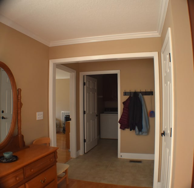 hallway with visible vents, washer / dryer, crown molding, and baseboards