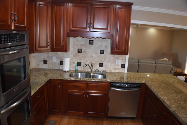 kitchen featuring a sink, backsplash, stainless steel appliances, crown molding, and light stone countertops