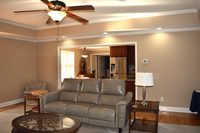 living area with baseboards, crown molding, and light wood finished floors