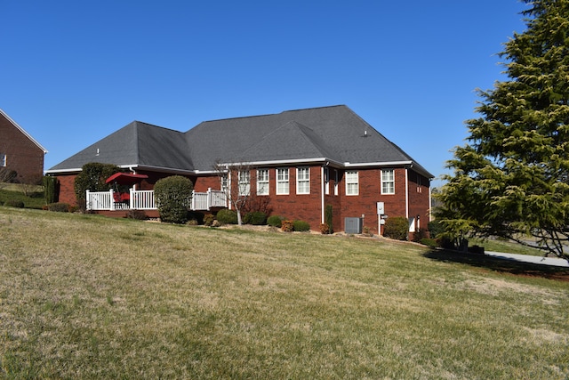 back of house with brick siding, central AC, a deck, and a lawn