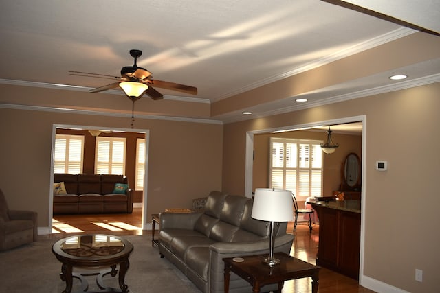 living room featuring a ceiling fan, a healthy amount of sunlight, and ornamental molding