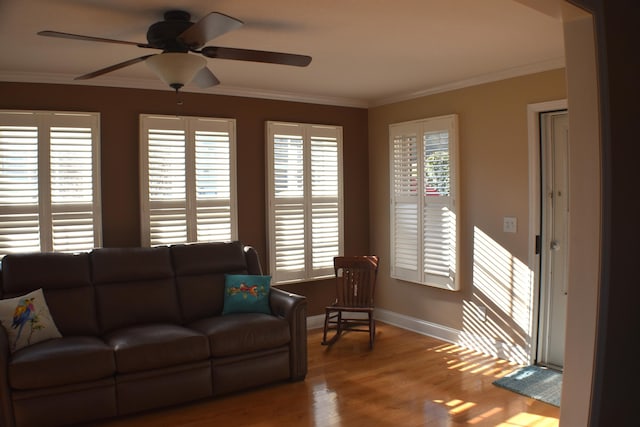 living room with a ceiling fan, wood finished floors, baseboards, and ornamental molding