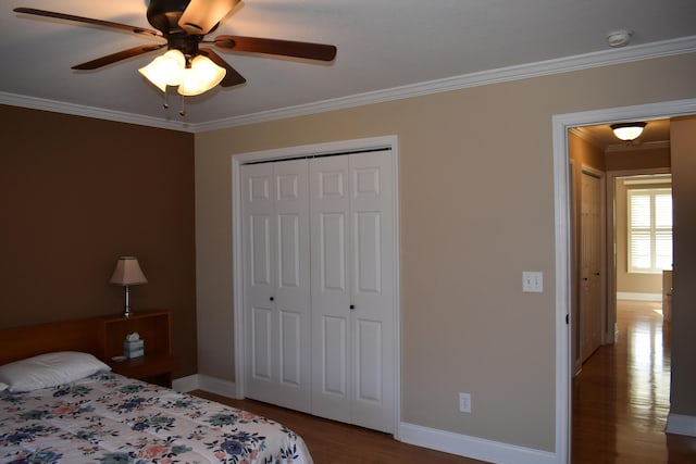 bedroom featuring ornamental molding, a ceiling fan, wood finished floors, a closet, and baseboards