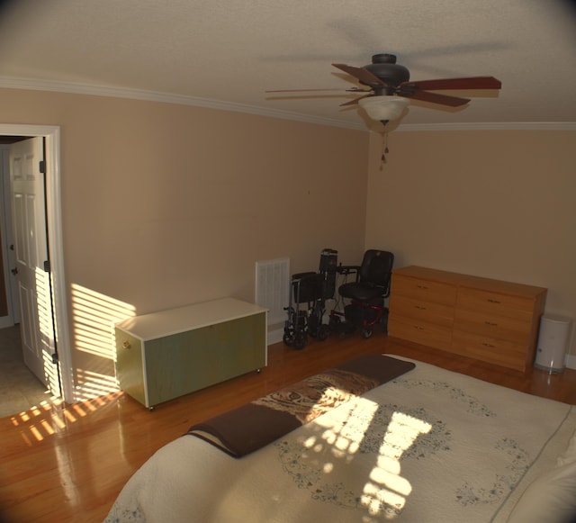 bedroom featuring ceiling fan, visible vents, light wood finished floors, and ornamental molding