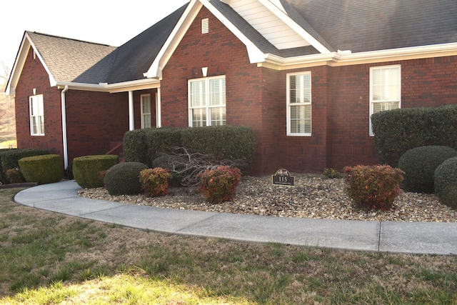 view of front facade featuring brick siding and a shingled roof