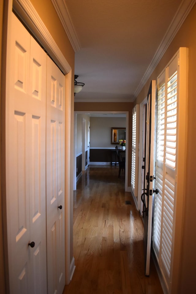 corridor featuring baseboards, wood finished floors, and ornamental molding