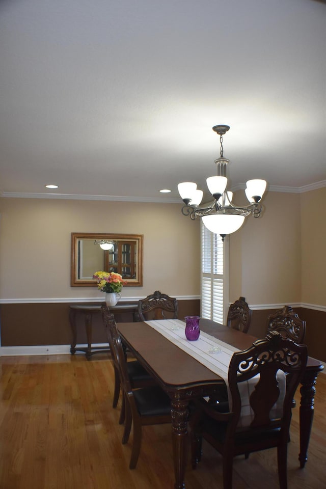 dining space with ornamental molding, an inviting chandelier, and wood finished floors